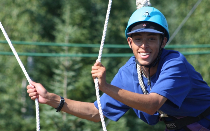 a person smiles while navigating a ropes course